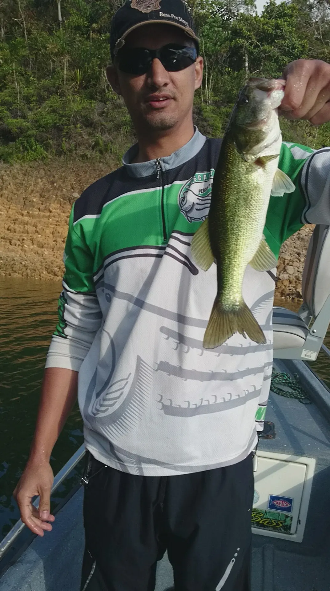 Un black bass mediano es levantado del agua mostrando su cuerpo moteado.