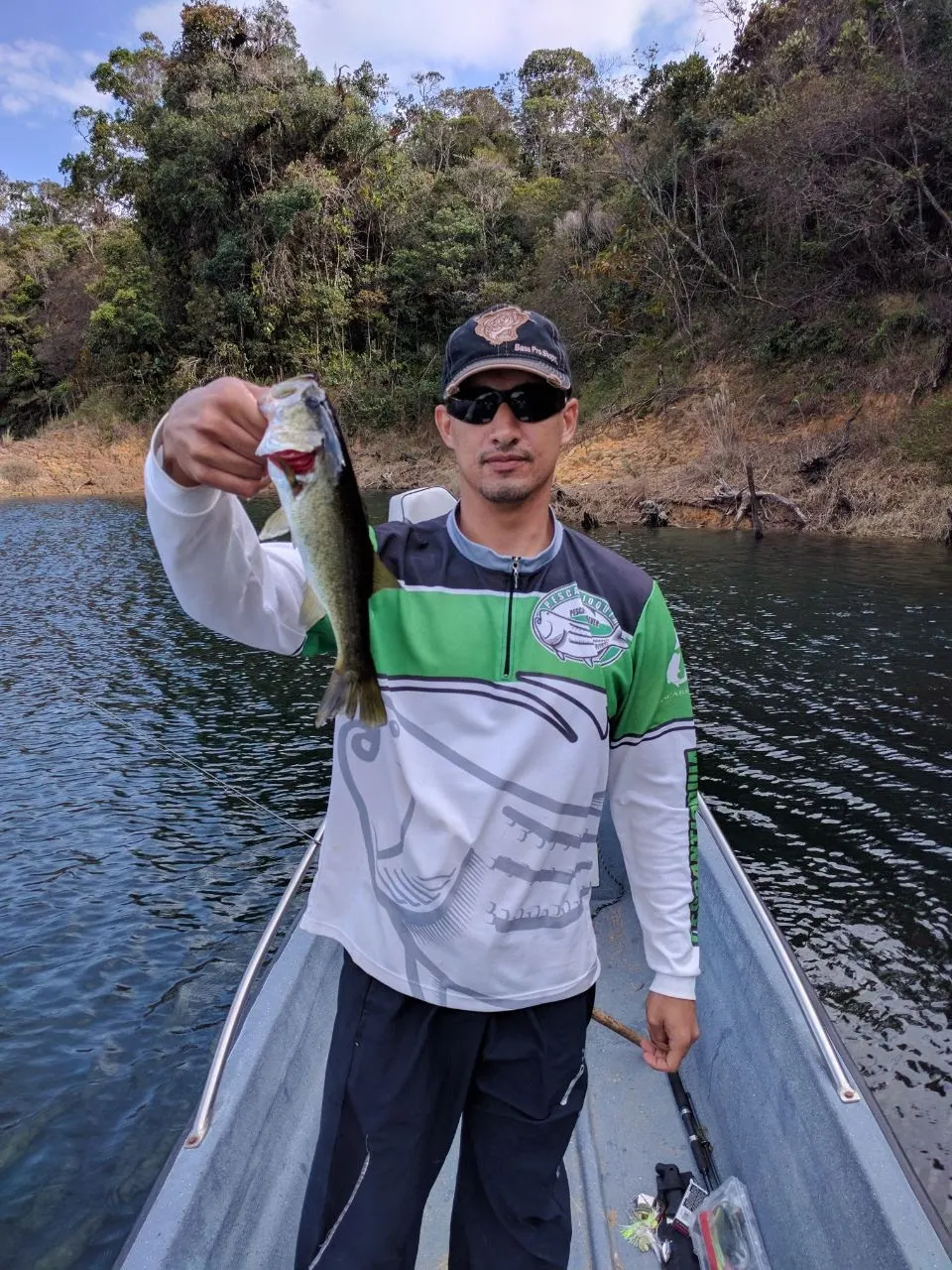 Un black bass es levantado del agua mostrando el señuelo watermelon enganchado.