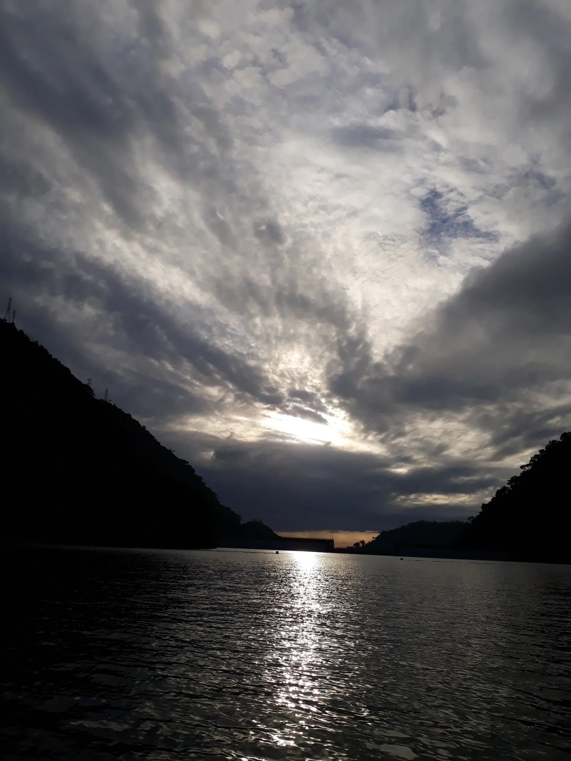 El embalse de Amaní en la madrugada, con una bruma ligera sobre el agua verde bordeada de selva.