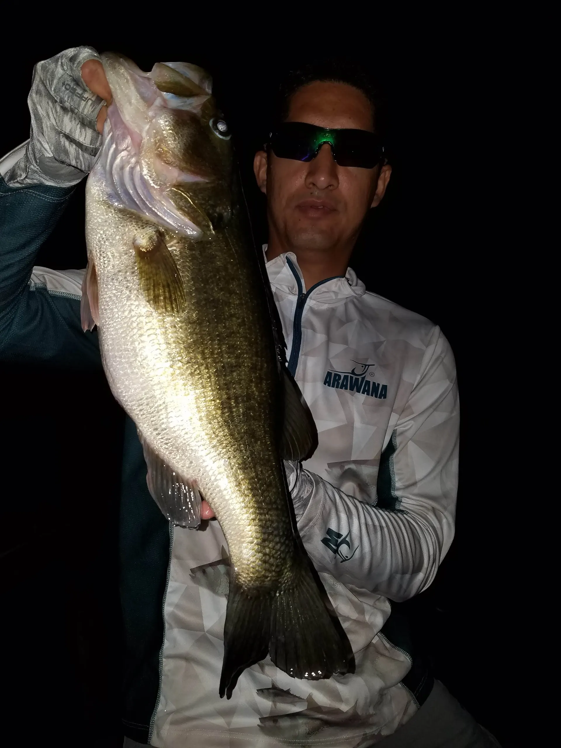 Un pescador sostiene con las dos manos otro de los grandes bass capturados esa noche.