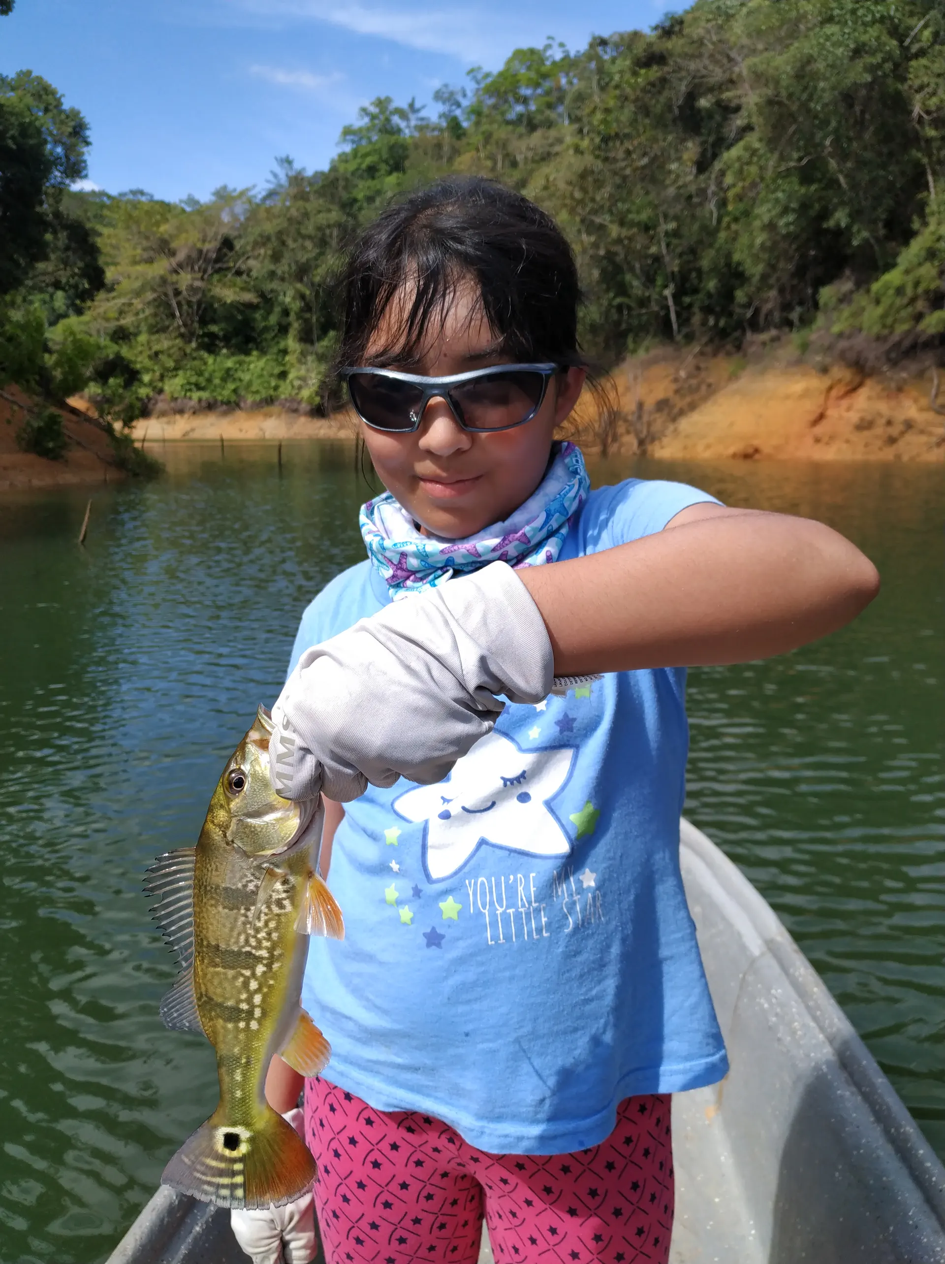 Valeria lanza su caña desde el bote, concentrada, sobre el embalse de Playas.