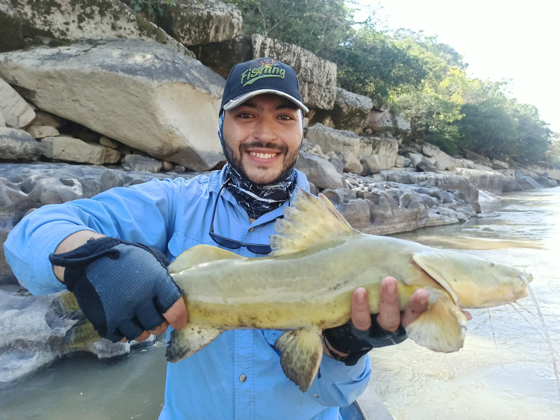 Diego sostiene otro bagre amarillo capturado con carnada en el raudal.