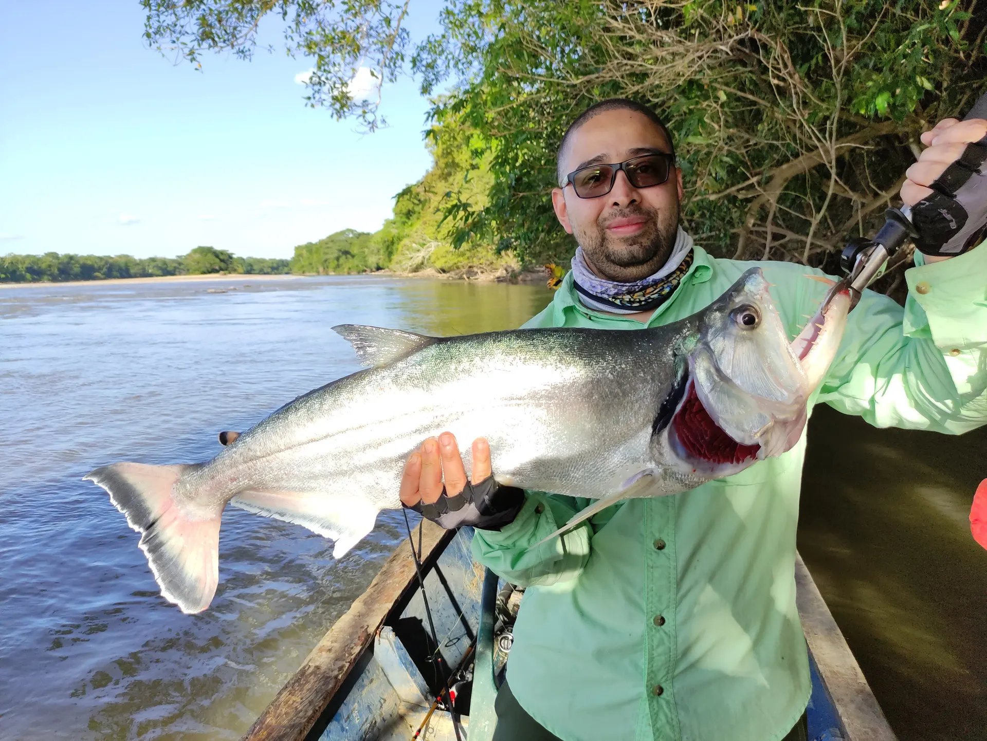 Dayro sostiene con orgullo una payara de colmillos visibles capturada en las cachiveras.
