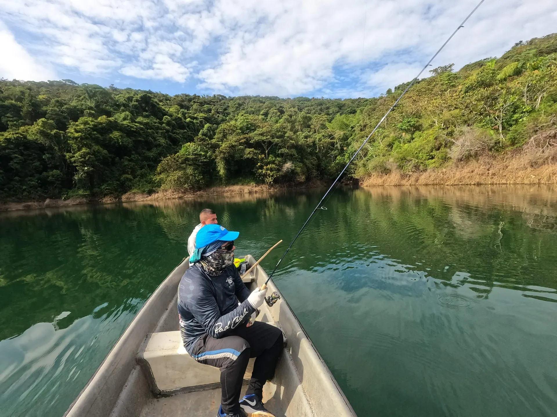 El bote navega por una cala estrecha del embalse de Jaguas rodeada de vegetación densa.