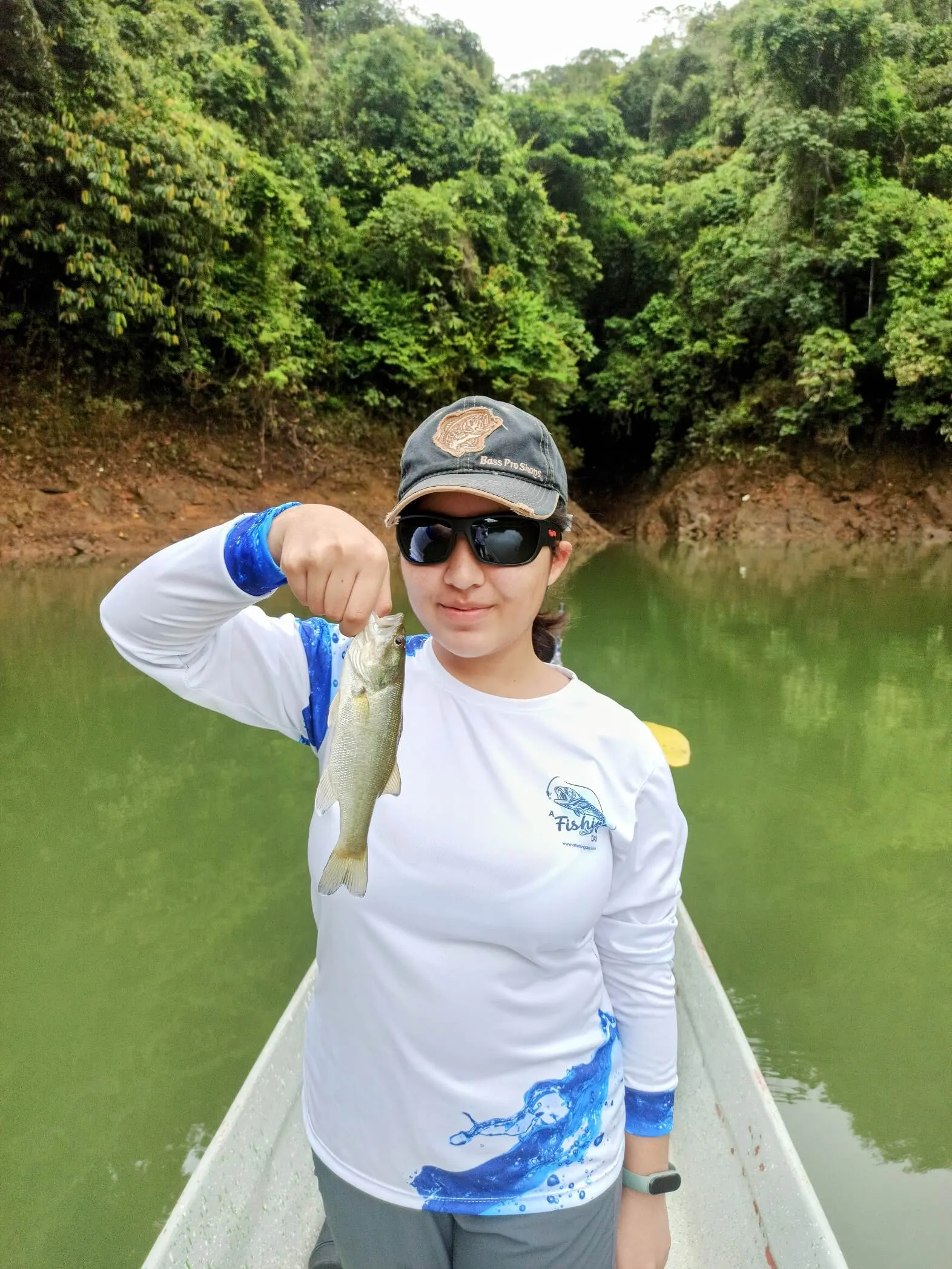 Un pescador sostiene un black bass mediano recién capturado en el bote sobre el embalse de Punchina.